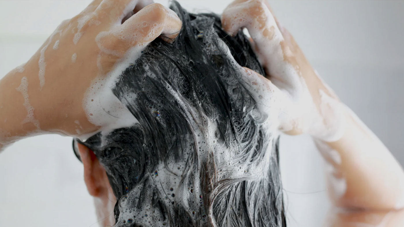 Woman washing hair, a guide to finding your scalp type with Rootonix shampoos at Dear Glow Singapore